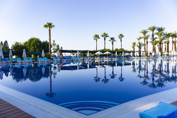 Alberca techada, alberca al aire libre y sombrillas en la alberca