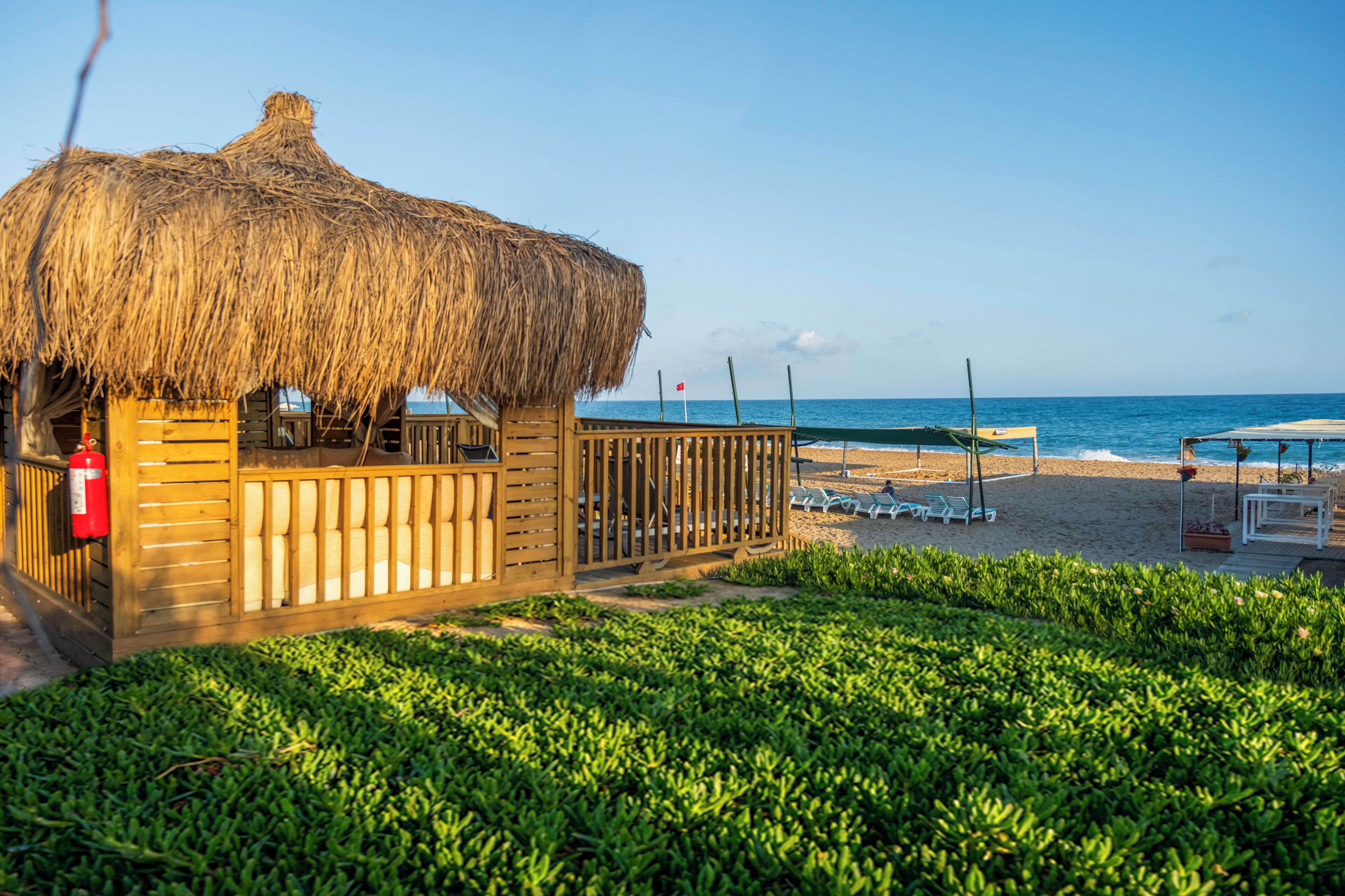 A beachside wooden structure with a thatched roof, a fenced area, and a view of the ocean.