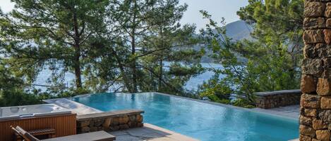 Ein Poolbereich mit Liegestühlen und einer Steinmauer.