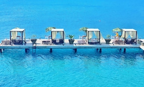 A floating platform with four covered seating areas, each with a chair and a small table, overlooking a clear blue body of water. - Marmaris Bay Resort - Adults Only - All inclusive (Marmaris)