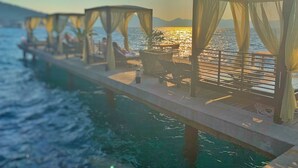 Une jetée dotée de toiles d’ombrage et de chaises longues, offrant une vue sur la mer.