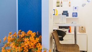 A room with a desk, chair, and a wall with framed pictures and a calendar.