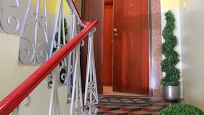 A staircase with a red handrail leading to a wooden door.