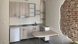 A compact kitchen with a built-in sink, a small refrigerator, and a wooden cabinet.