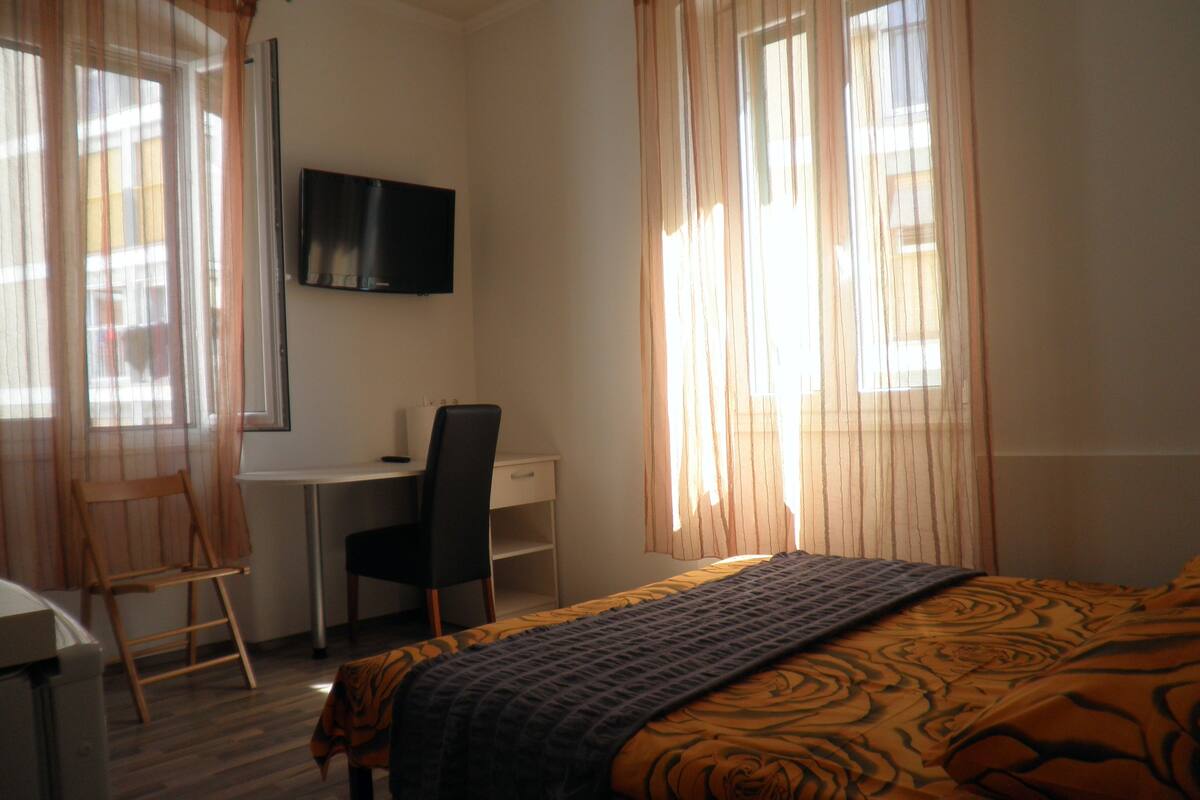 Un dormitorio con cama, escritorio, silla y televisor en la pared.
