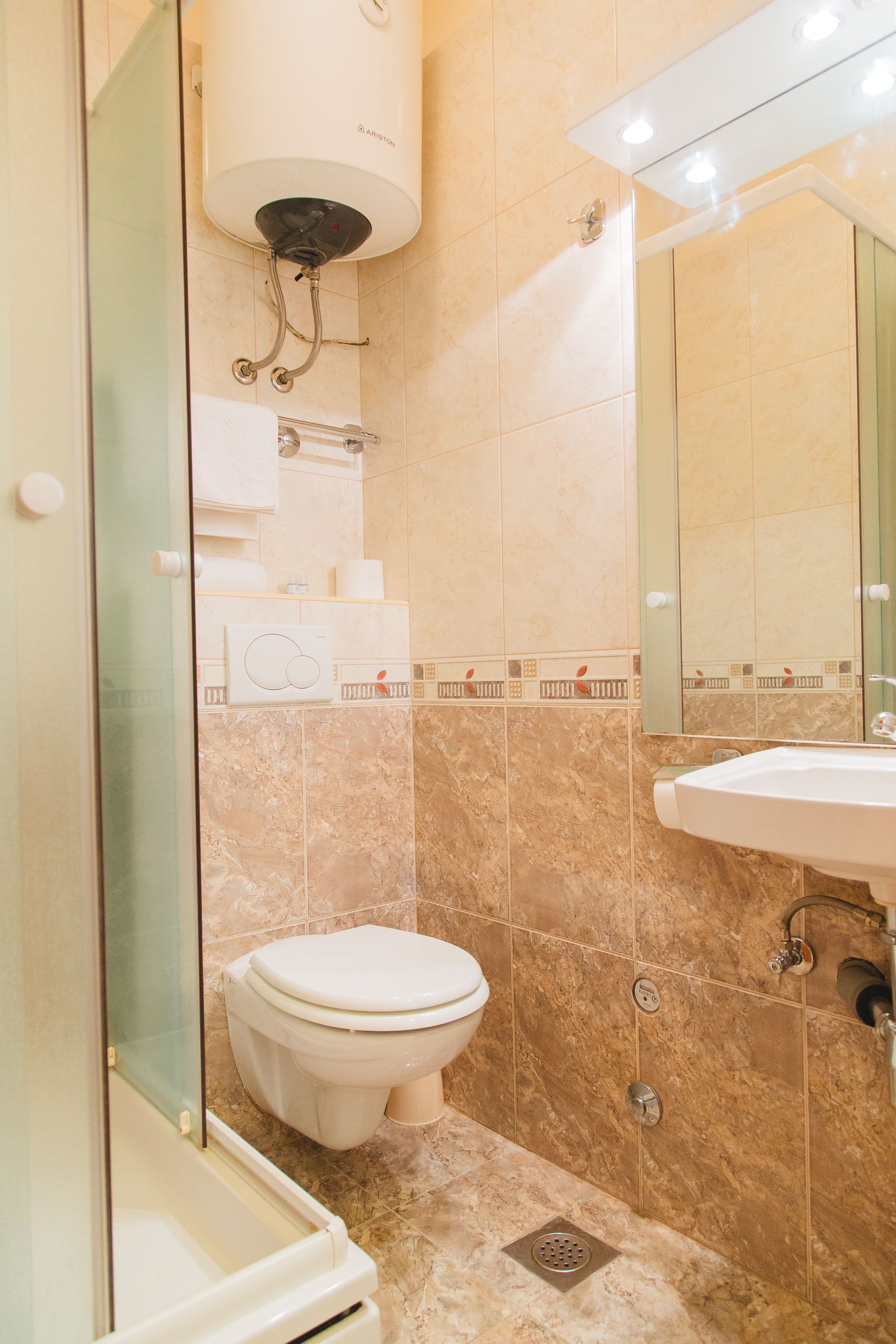 A bathroom with a toilet, a sink, a shower, and a mirror.