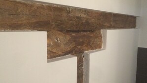 Una struttura in travi di legno su una parete bianca.