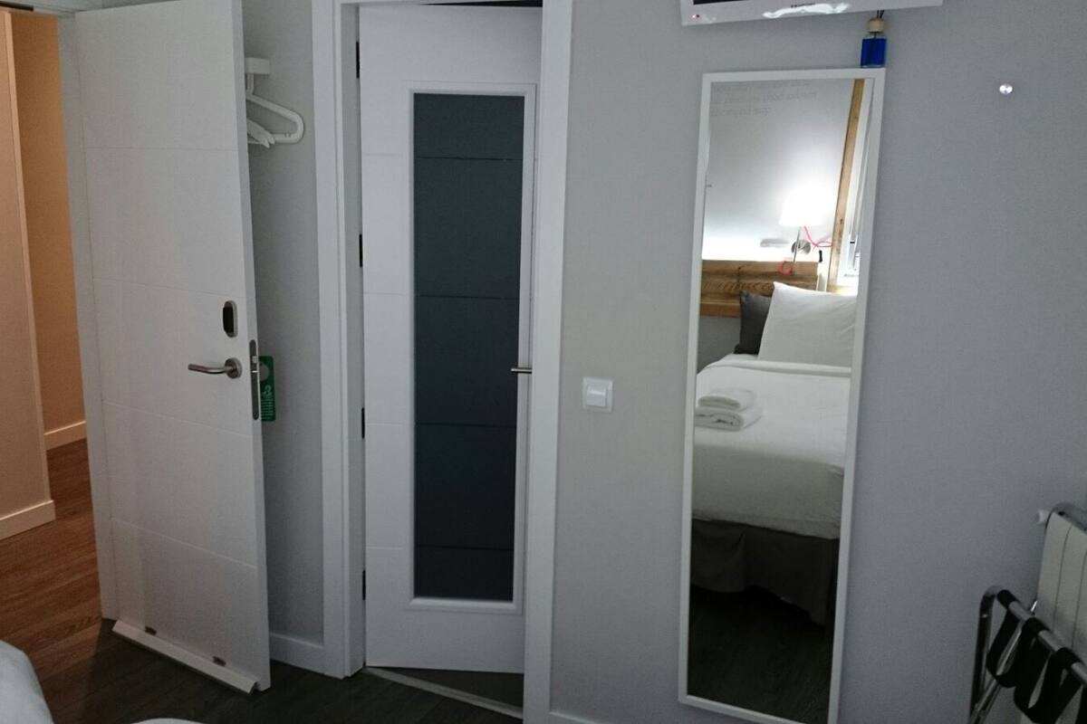 Una camera d'albergo con un letto, una porta e un termosifone.