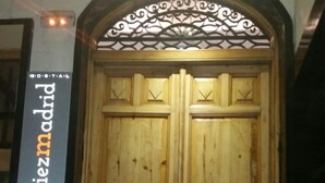Una porta doppia in legno con elaborate sculture e un arco decorativo in metallo sopra di essa.