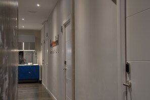 A hallway with a blue cabinet, a stainless steel refrigerator, and a door labeled "Hospital." - Diezmadrid Hostal (Madrid)