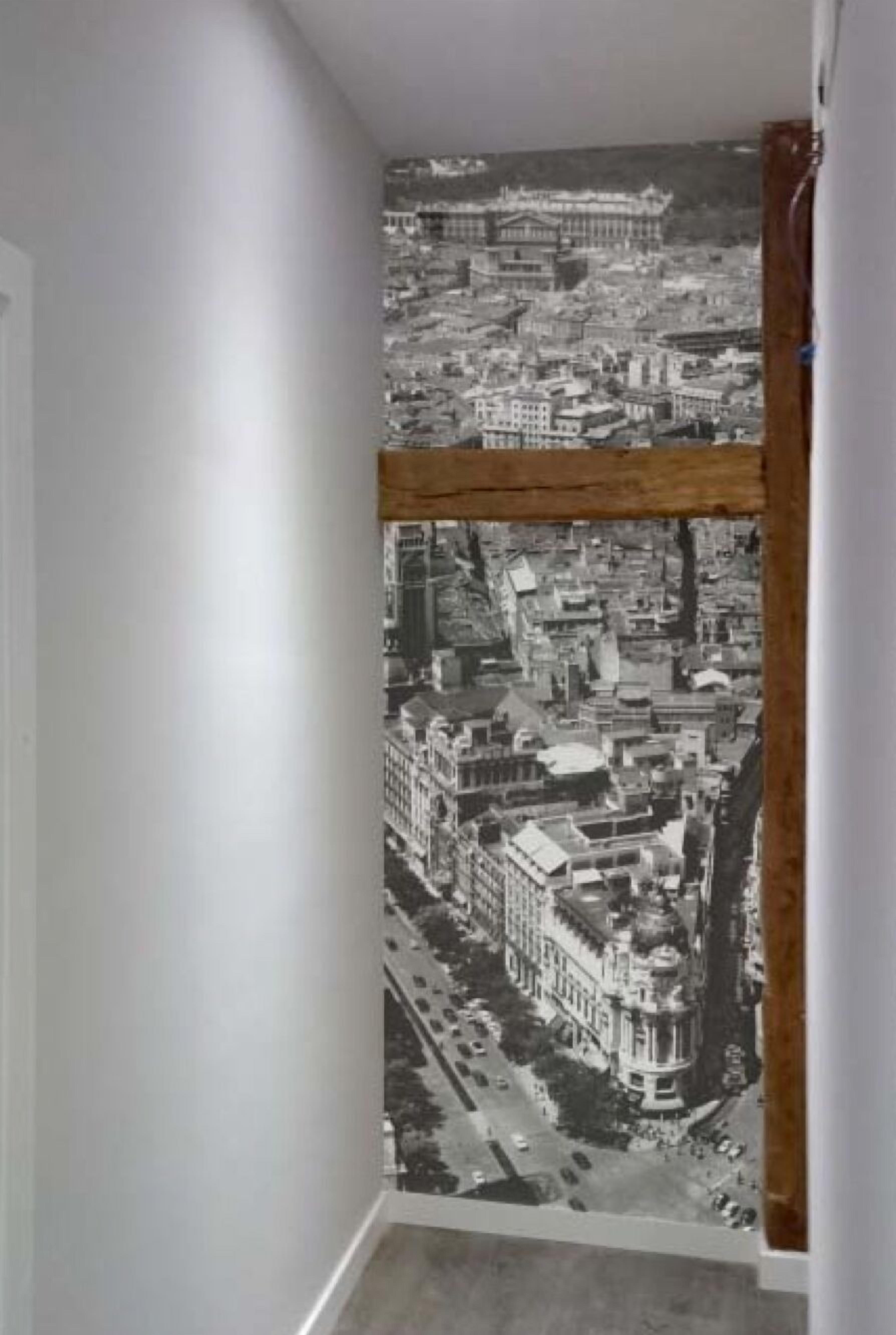 A room with a large window featuring a black and white cityscape view.