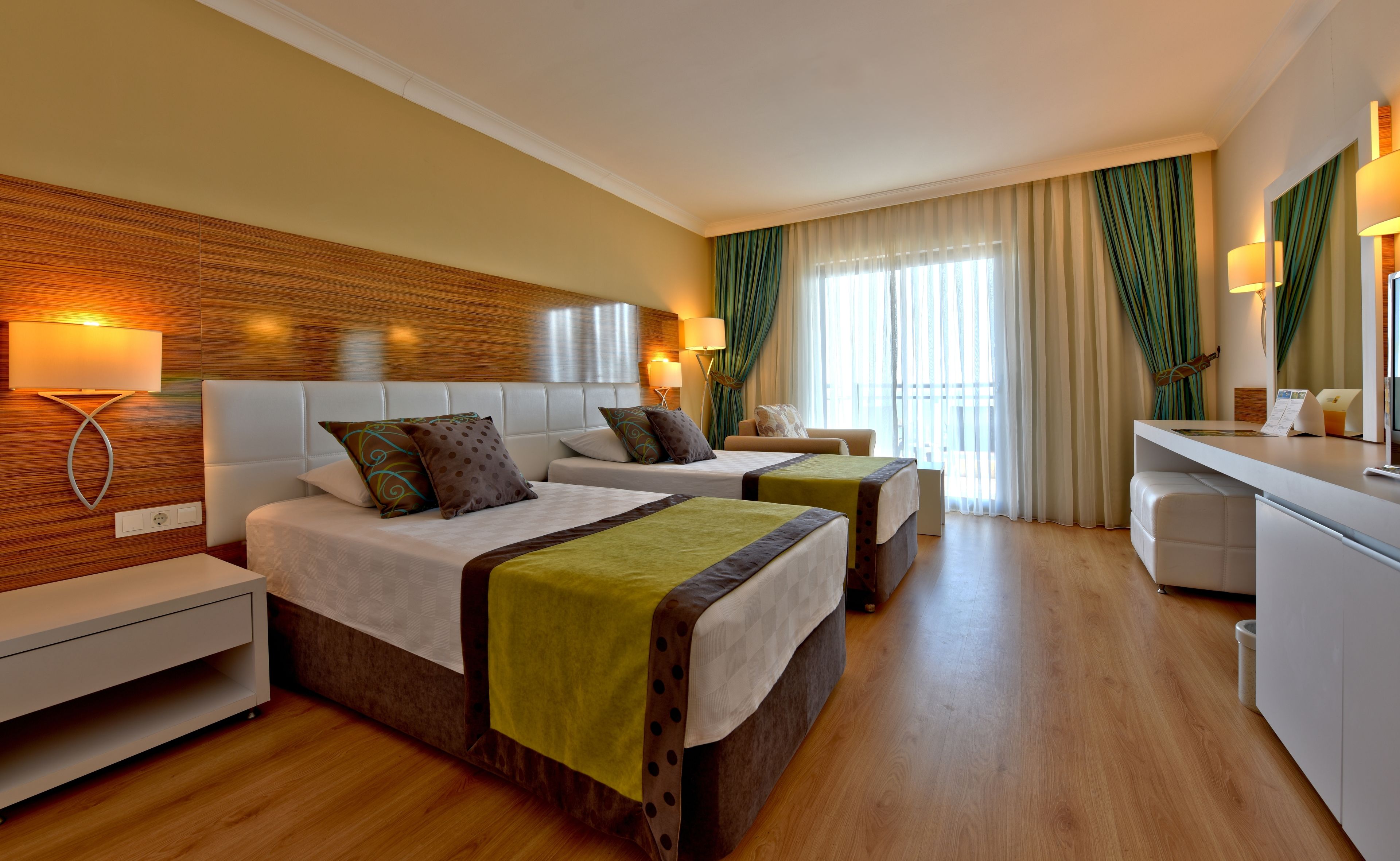 A hotel room with two beds, a desk, and a chair.