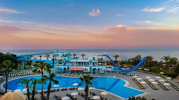 Een resort met een groot zwembad, een glijbaan en uitzicht op de oceaan.