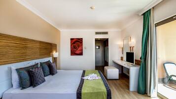Habitación de hotel con cama, escritorio, silla, televisión y ventana con cortinas.