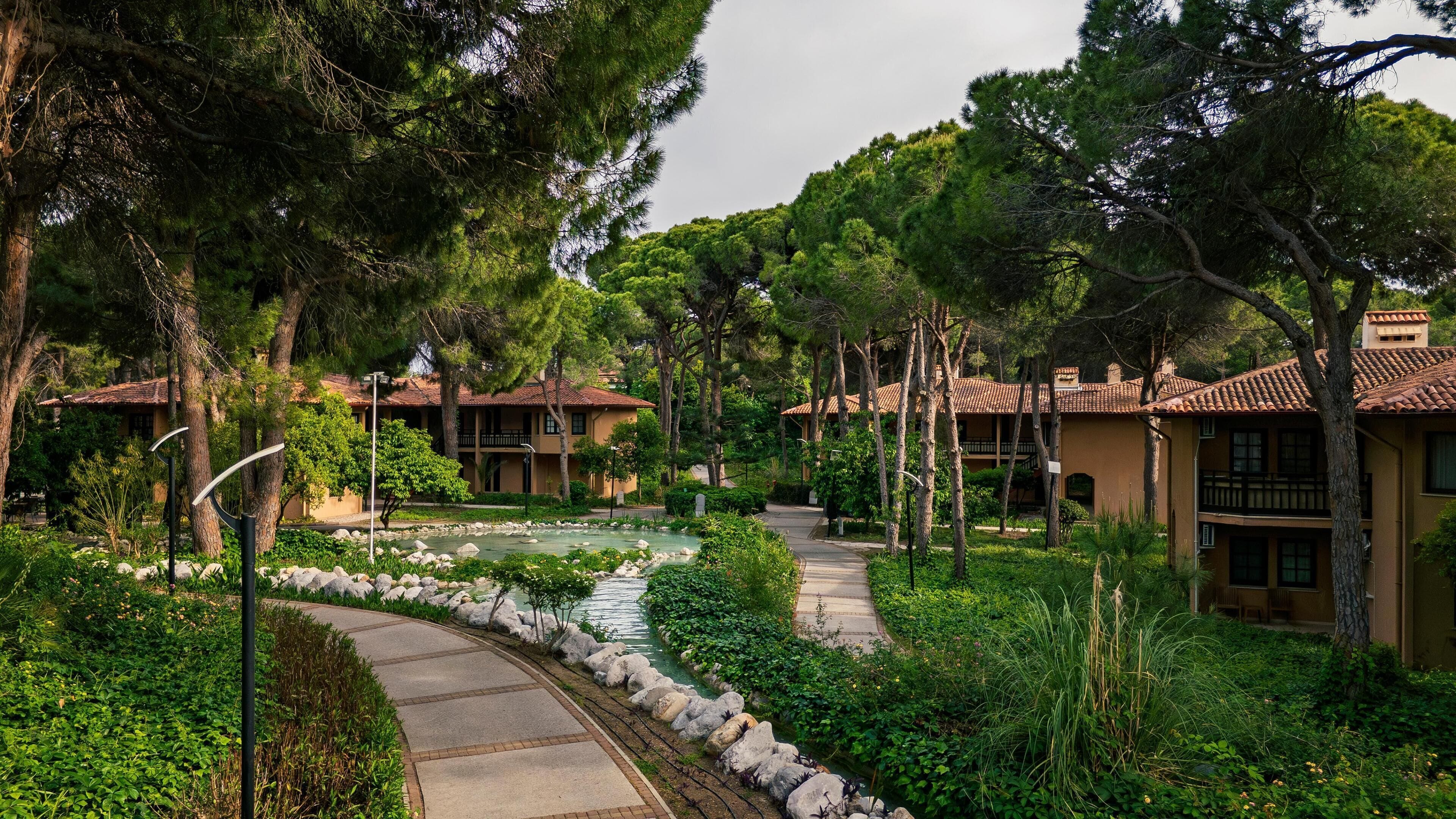 A resort with multiple buildings, a central water feature, and a stone pathway.