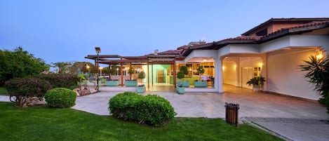 A modern house with a covered patio, a well-maintained lawn, and a large driveway.