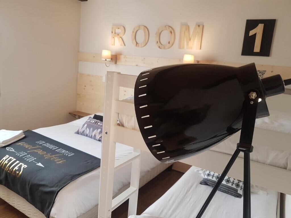 A bedroom with a bed, a desk, a lamp, and a wall with the word "ROOM" and the number "1".