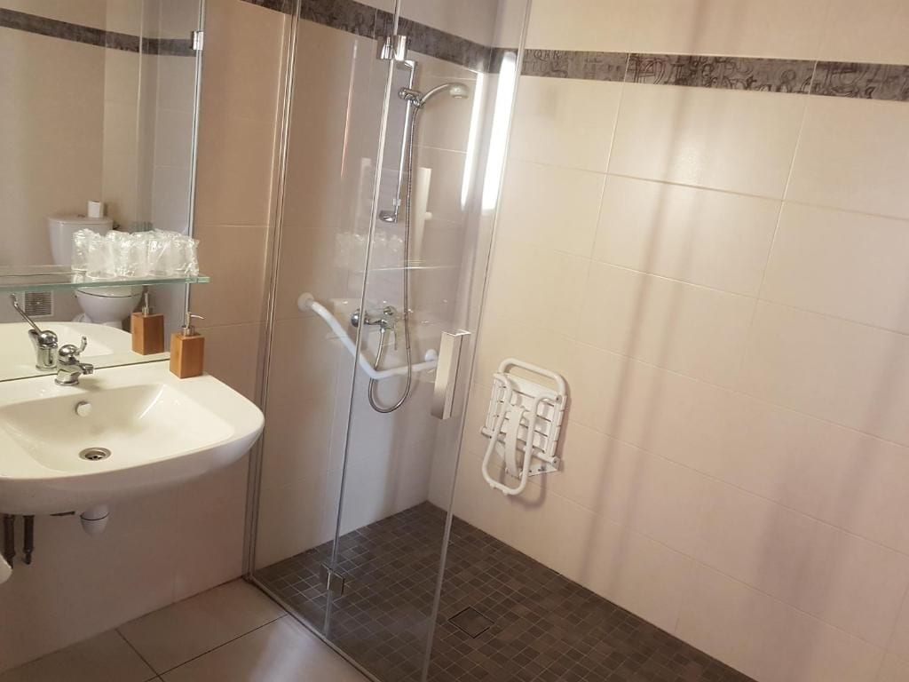 A bathroom with a glass-enclosed shower, a sink, and a towel rack.