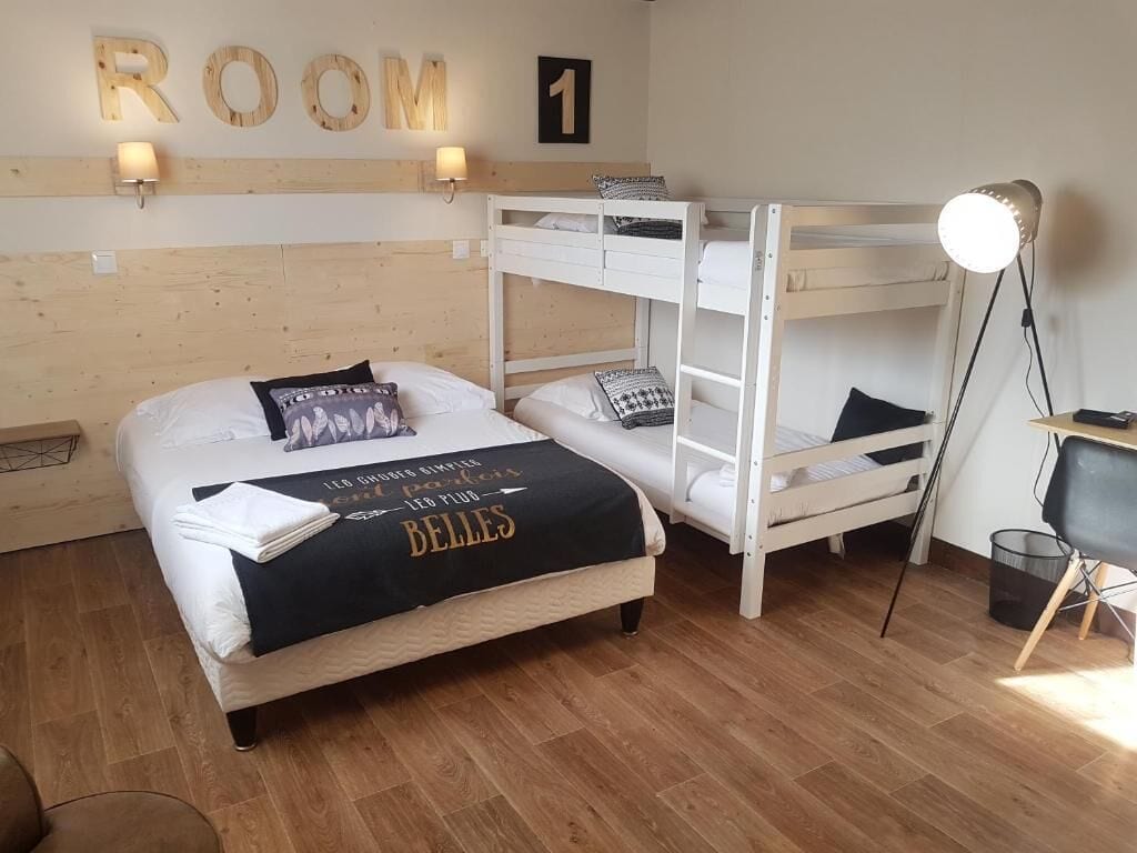 A room with a bunk bed, a desk with a chair, a lamp, and a wall-mounted sign reading "ROOM 1".