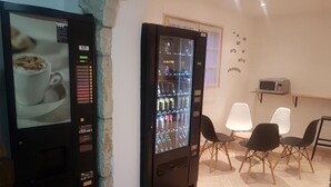 A room with a vending machine, a microwave, and a seating area with chairs. - Le Sainte Florence (Essarts en Bocage)