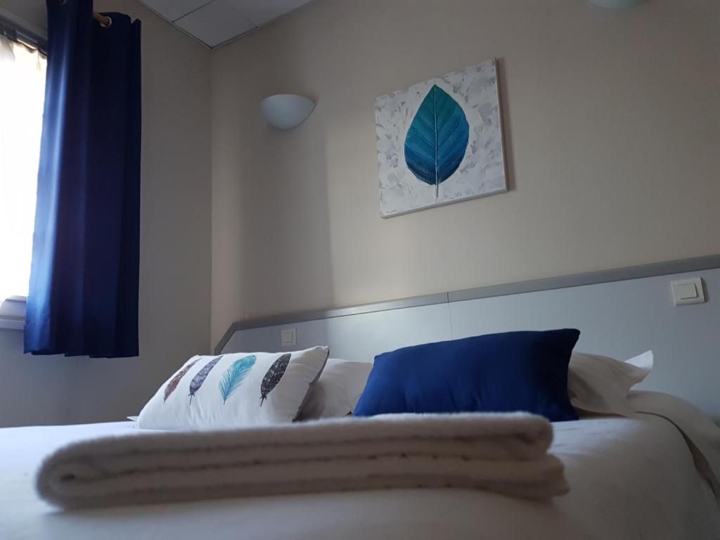 Habitación de hotel con cama, almohadas, una obra de arte en la pared y una ventana con cortinas.
