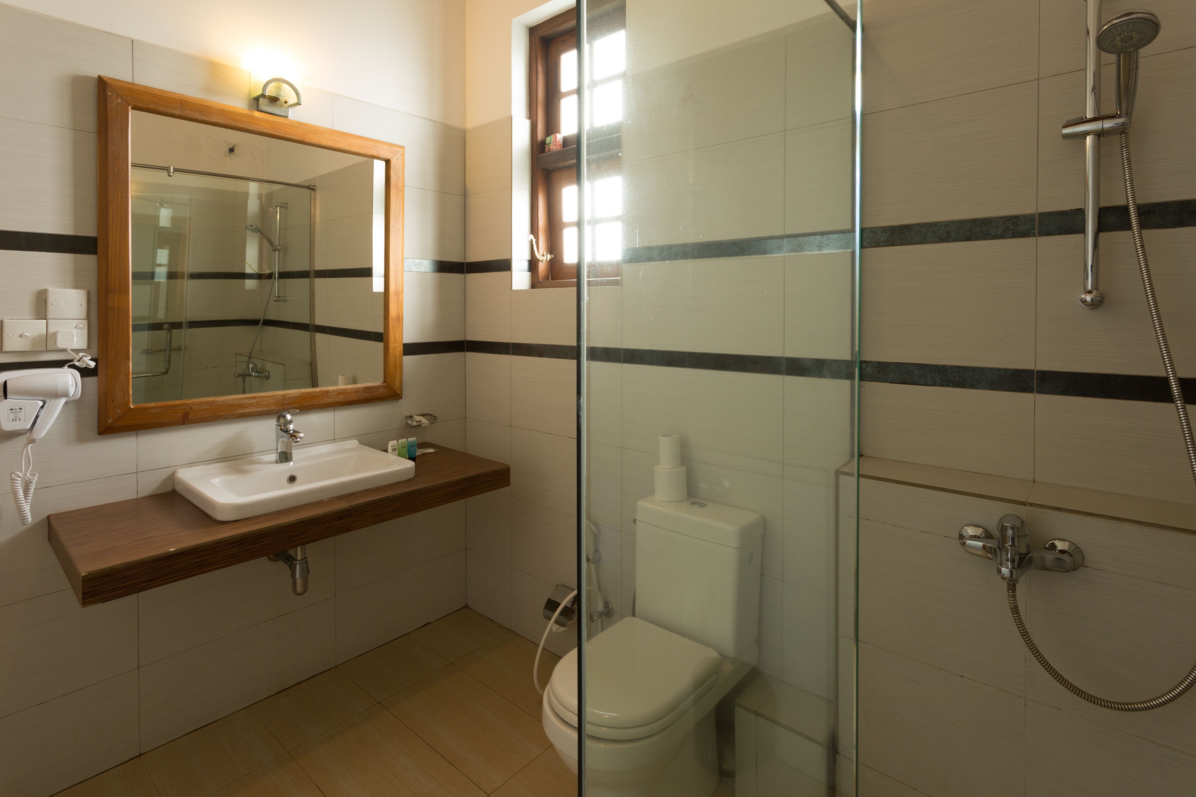 A bathroom with a glass-enclosed shower, a wooden vanity with a sink, and a toilet.