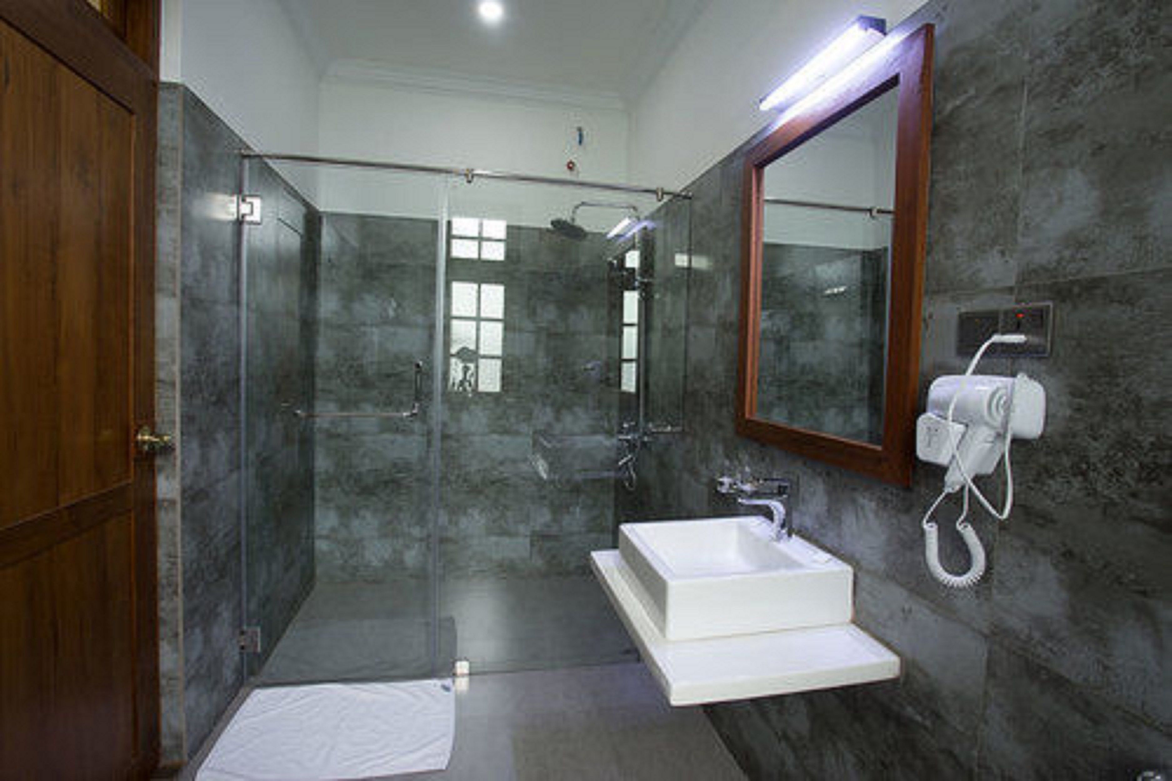 A modern bathroom with a glass-enclosed shower, a white sink, and a built-in hairdryer.
