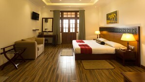 A hotel room with a bed, bedside table, lamp, TV, and a desk with a chair. - Heaven Seven Nuwara Eliya (Nuwara Eliya)