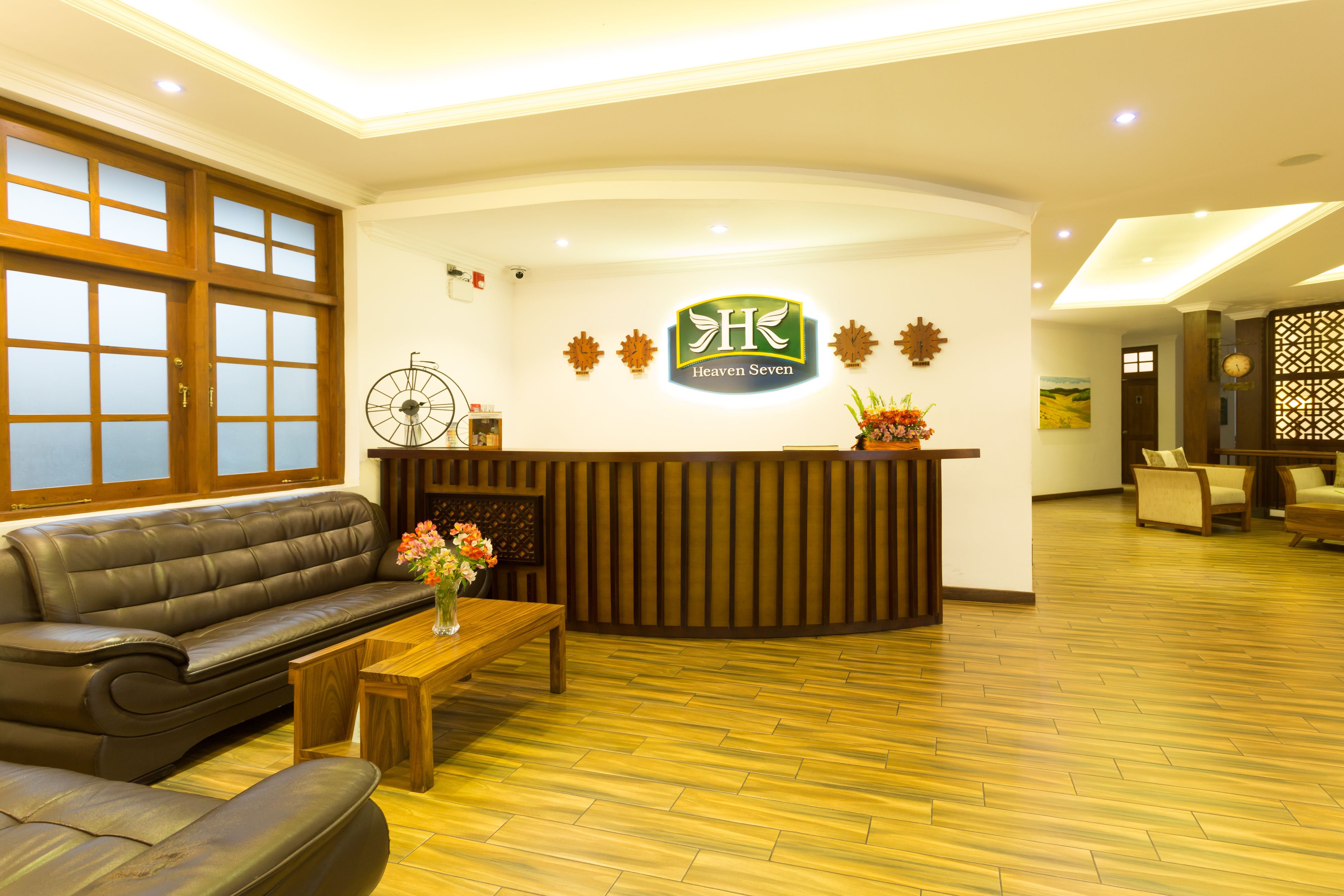 A reception area with a wooden reception desk, a leather sofa, a wooden coffee table, and a wall-mounted clock.