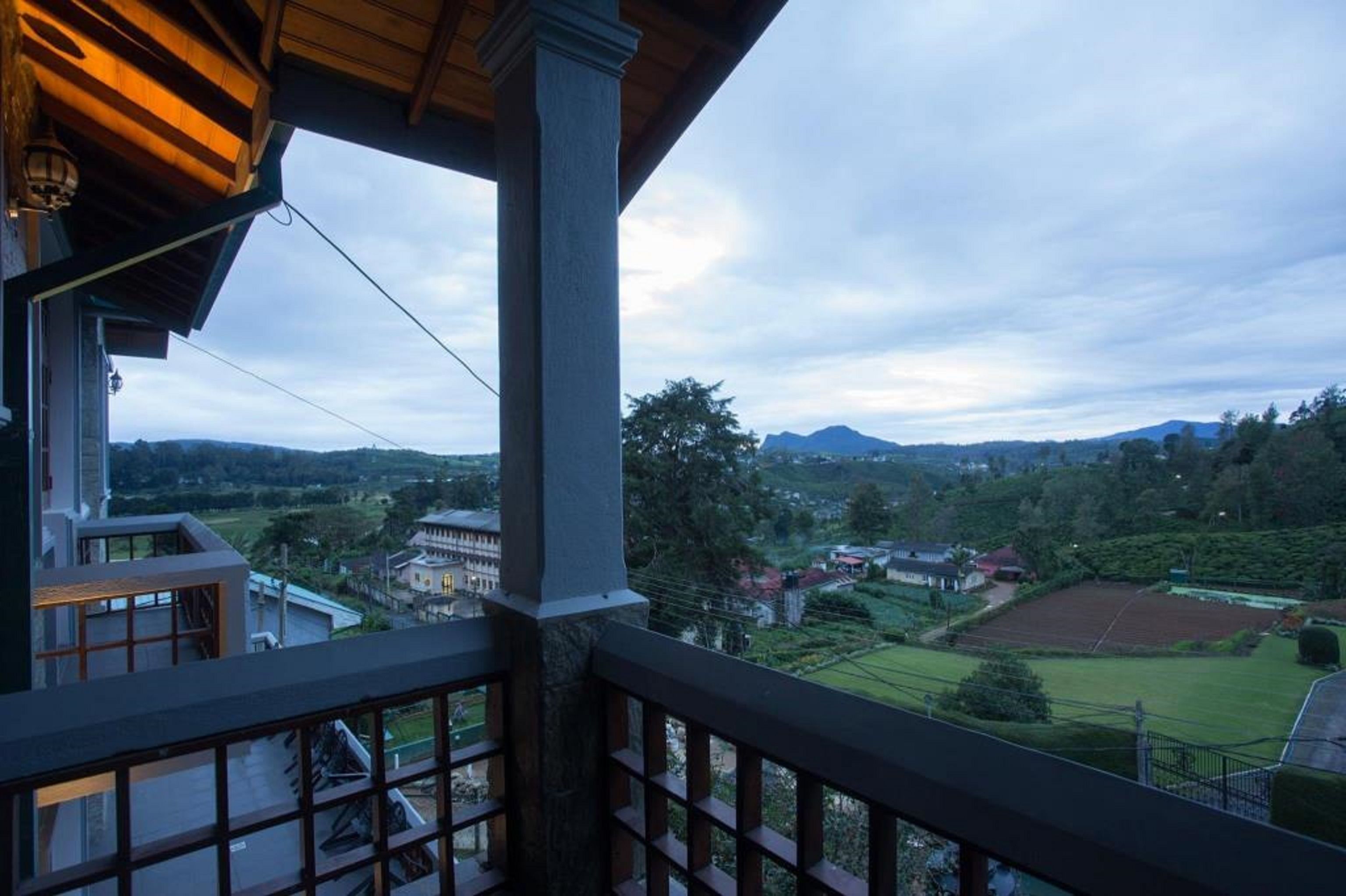 A balcony with a view of a rural landscape, including fields and a distant building.