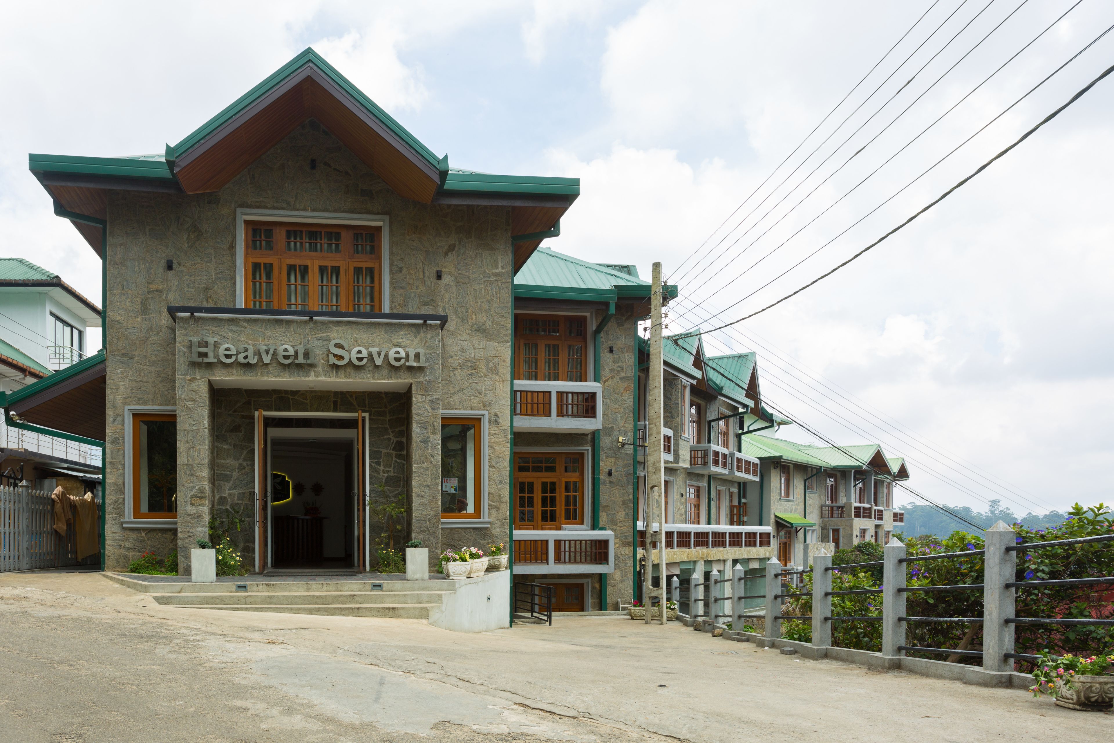 Un edificio de varios pisos con fachada de piedra y techo verde, con la leyenda 'Heaven Seven'.