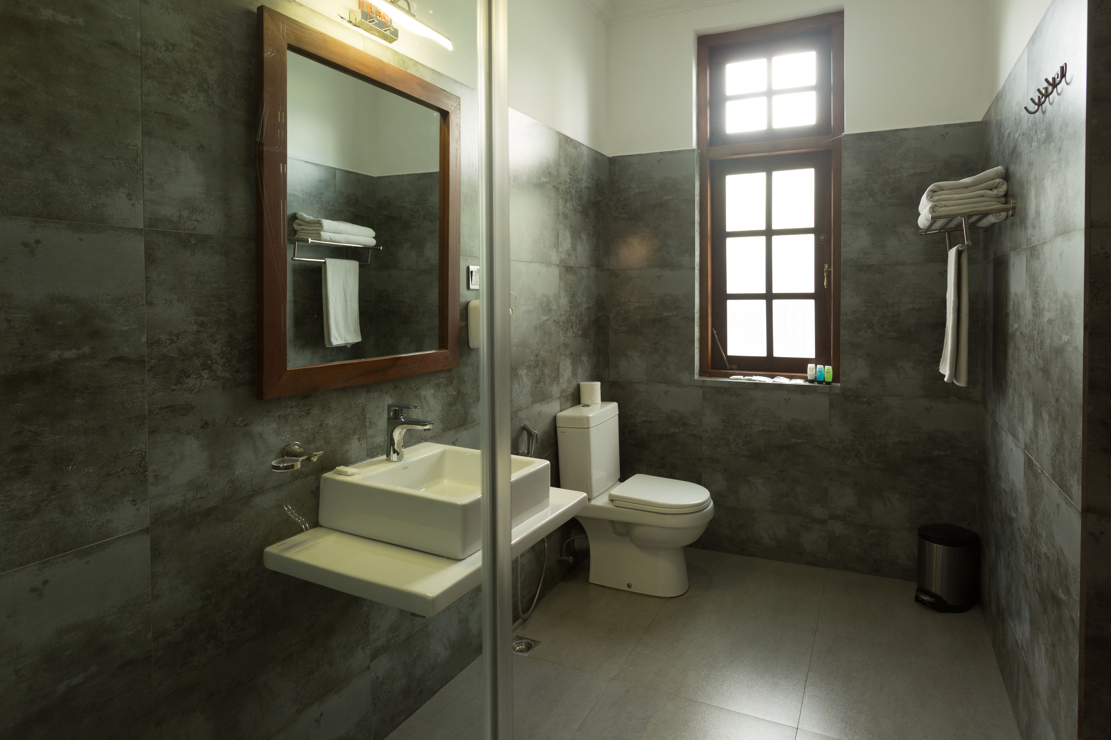 Un baño con un espejo grande, dos lavamanos, un inodoro y una ventana.