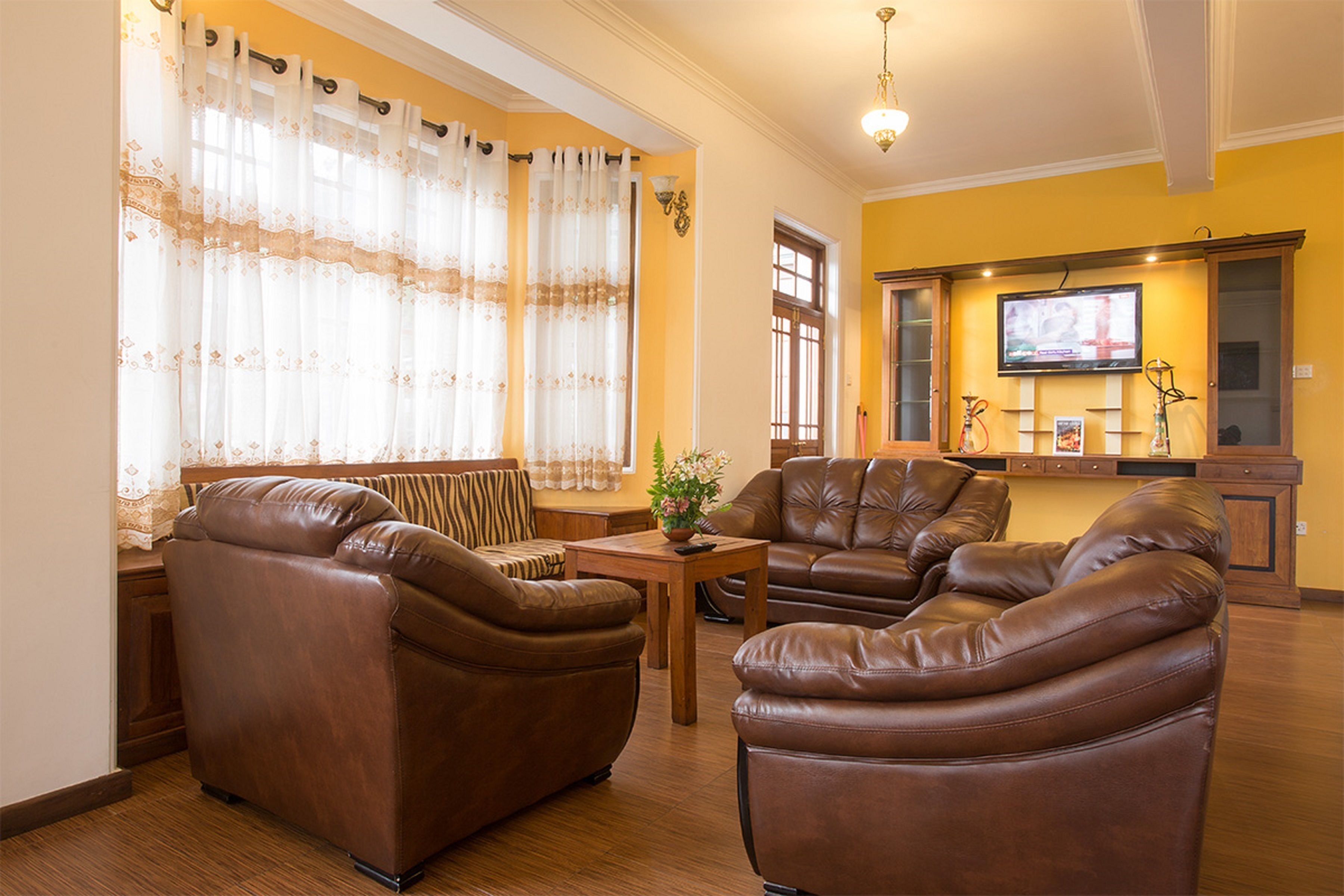 A living room with leather sofas, a wooden coffee table, and a television on the wall.