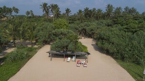 Ein Strand mit einer strohgedeckten Hütte, Liegestühlen und einem Schild.