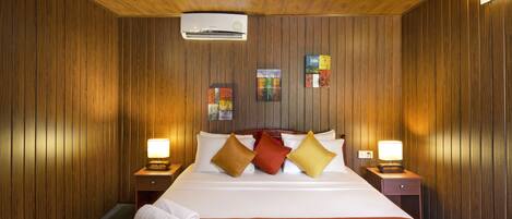 Habitación de hotel con pared de paneles de madera, cama con ropa blanca y dos mesitas de noche con lámparas.