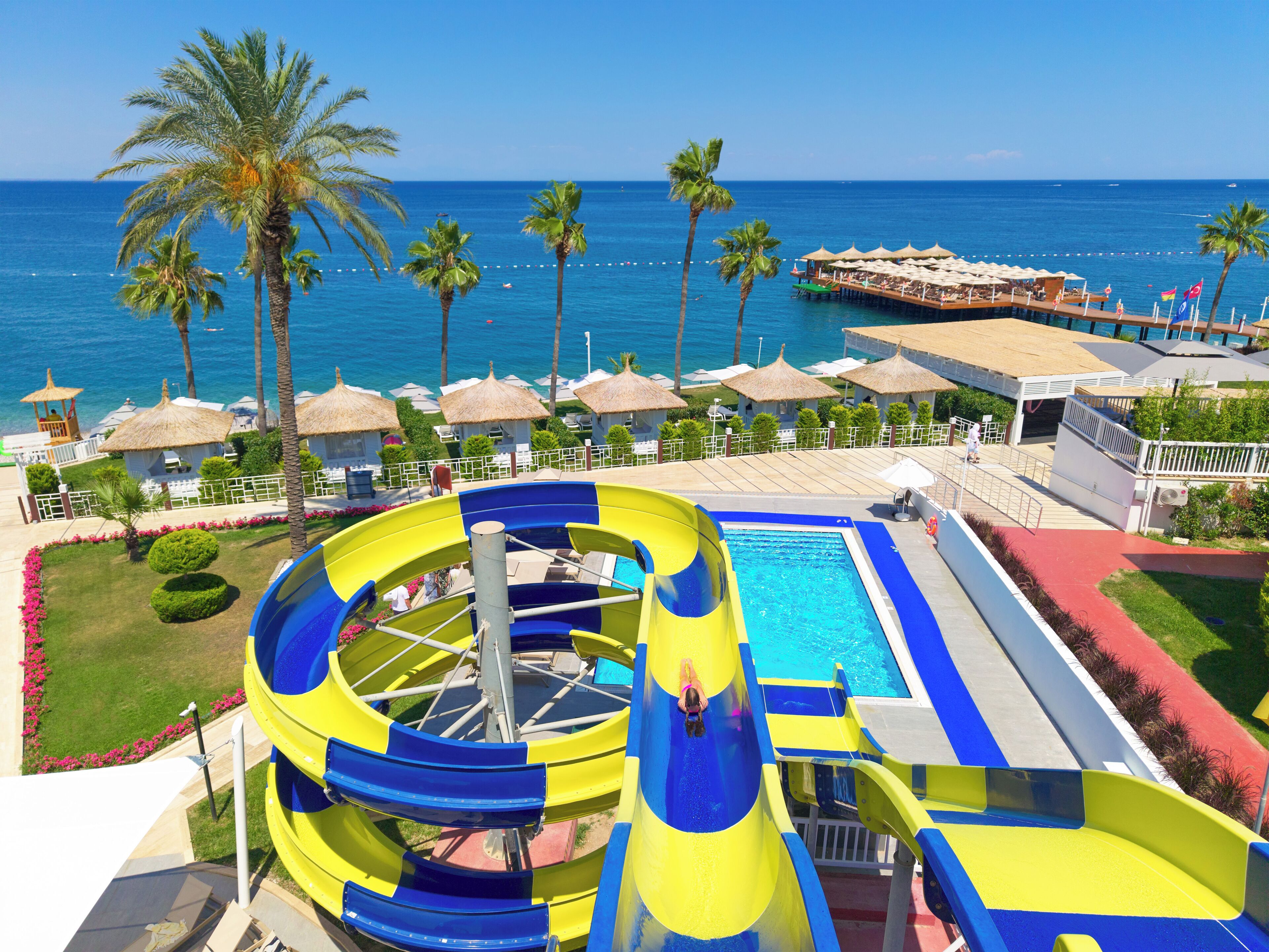 A water park with a large slide, a pool, and a view of the ocean.