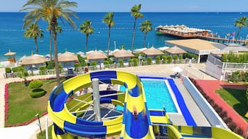 A water park with a large slide, a pool, and a view of the ocean.
