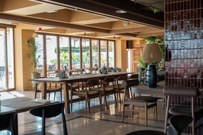Un vaste espace dédié à la salle à manger, doté de grandes fenêtres, de tables et de chaises en bois.
