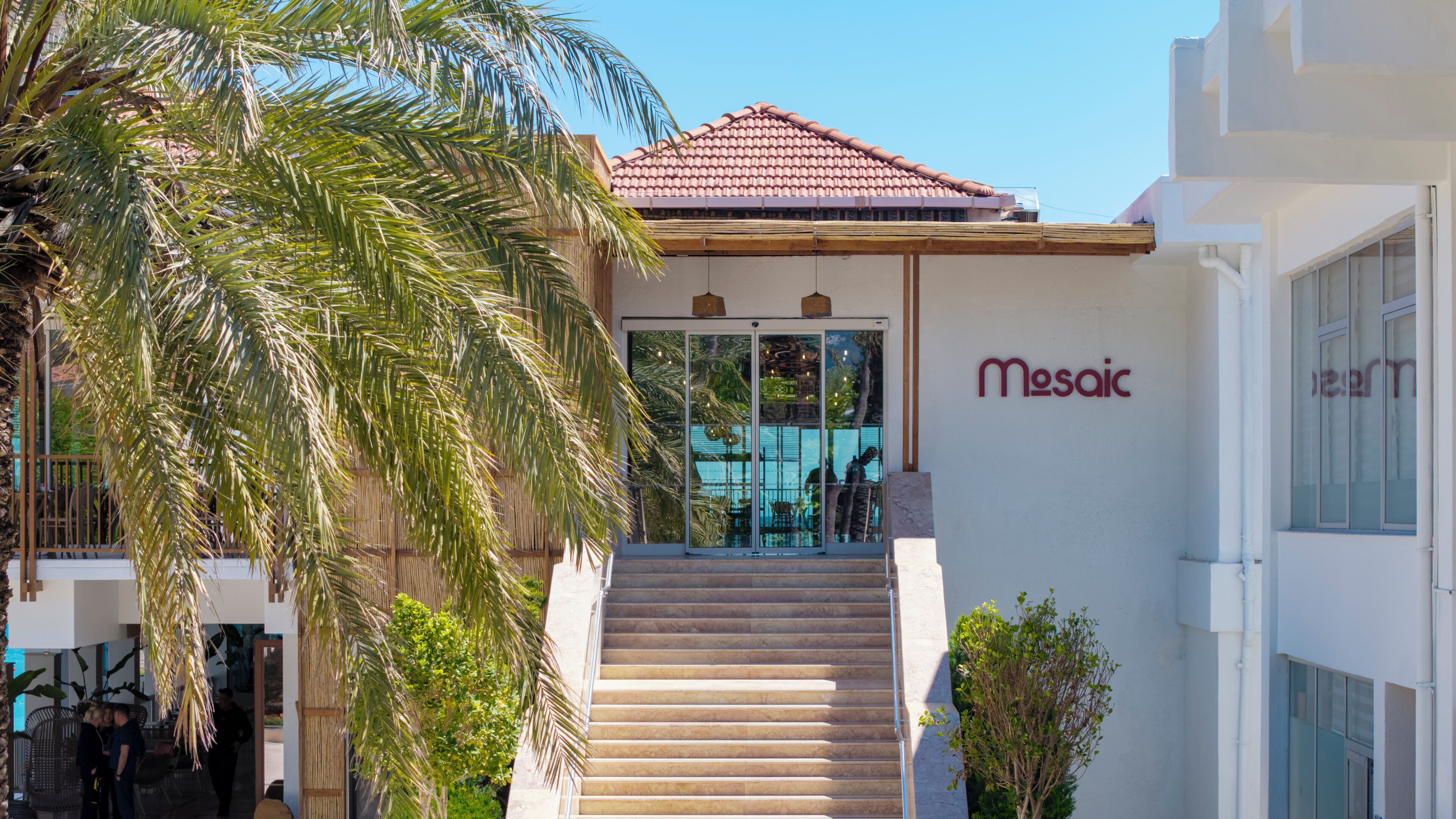 A building with a tiled roof, a staircase leading to a glass door entrance, and a sign reading 'Mesoic.'