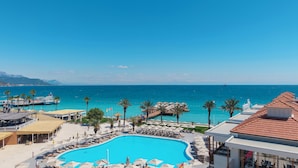 Un resort con piscina, sombrillas de playa, sillones de descanso y vistas al mar.