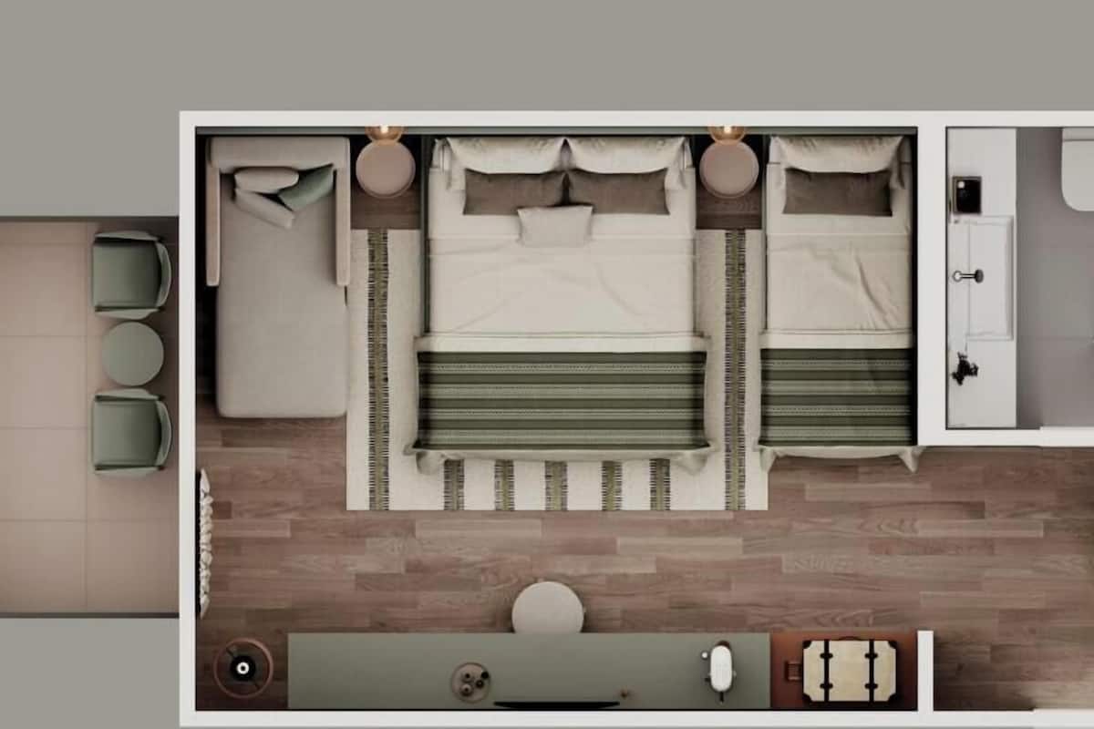 A hotel room with a bed, a sitting area with a table and chairs, a bathroom with a toilet and sink, and a small kitchenette.