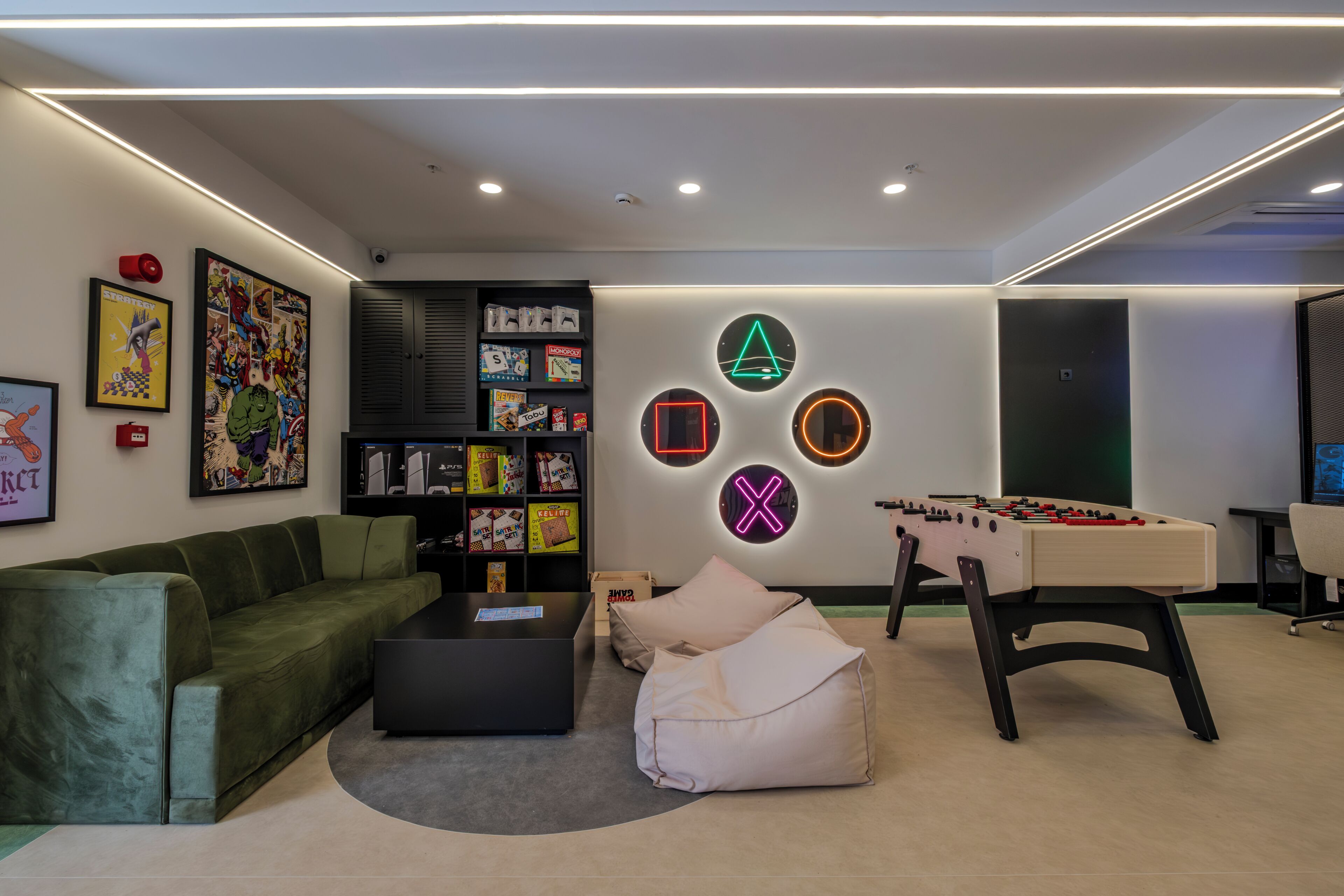 Una sala de estar moderna con un sofá verde, una mesa de centro, una mesa de fútbol y una estantería.
