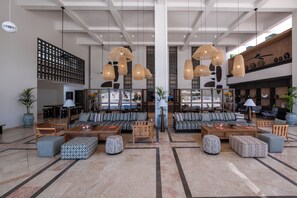 A spacious lobby with high ceilings, large windows, and a seating area with sofas and ottomans. - Corendon Hydros Club Kemer (Kemer)