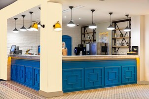 A modern kitchen with blue cabinetry, pendant lighting, and a tiled floor.