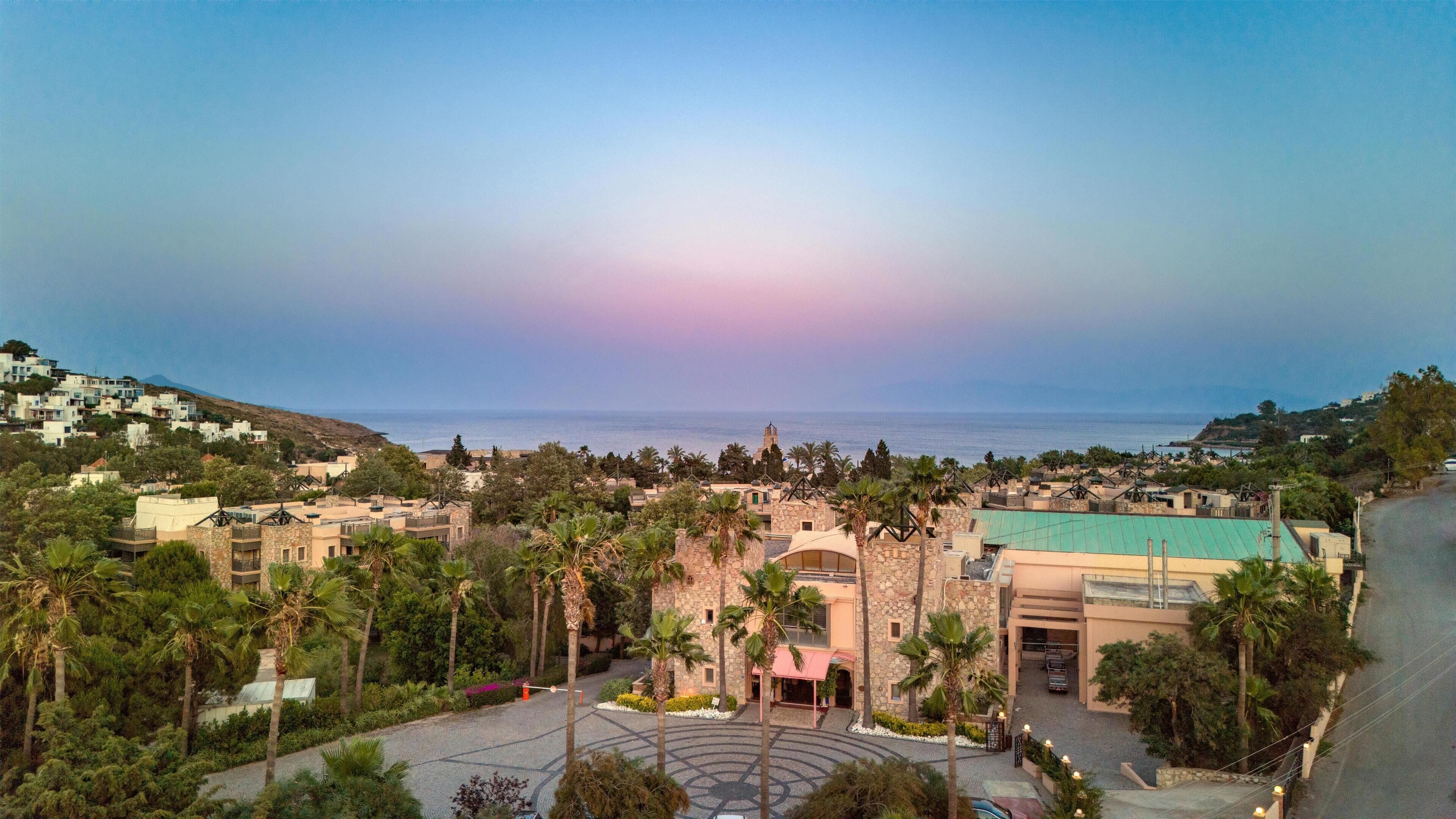 Una località balneare con un cortile centrale, palme e vista sul mare.