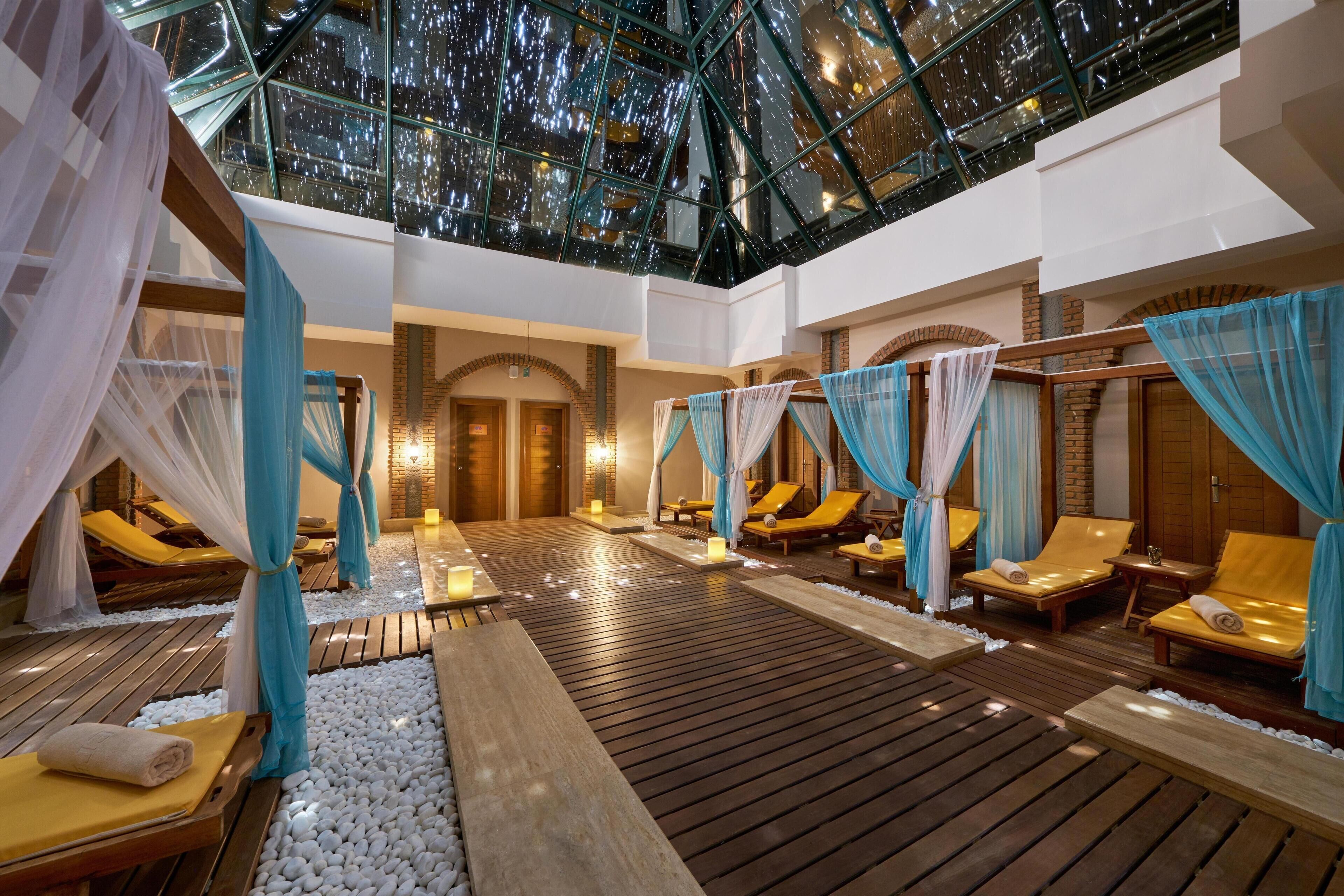 Un espacio de spa con suelo de madera, sillones acolchados y techo de cristal.