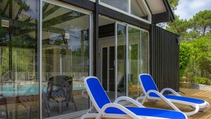 Un espace aménagé au bord de la piscine, avec deux chaises longues et une porte vitrée donnant accès à la piscine.