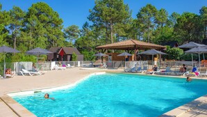 Une piscine entourée d’arbres et d’immeubles, avec des chaises longues et des parasols.