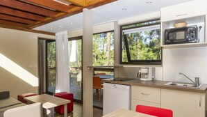 Une cuisine moderne équipée d’un four à micro-ondes, d’un évier et d’un lave-vaisselle. On y trouve également un coin repas avec des chaises rouges et une table.