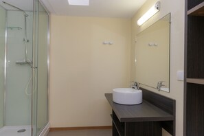 A modern bathroom with a glass-enclosed shower, a white sink, and a large mirror. - Les Oyats Sylvadoures (Carcans)